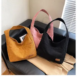 Detailed view of large corduroy tote bags in vibrant yellow, pink, and black colors