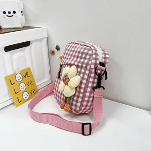 Detalle de un mini bolso bandolera de cuadros rosas con un lindo adorno de flores