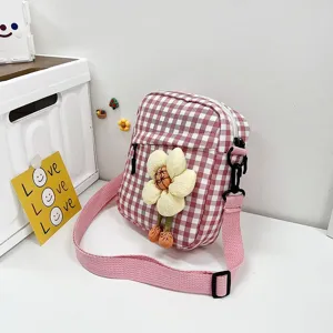 Vista detallada de un mini bolso bandolera de cuadros rosa con flor de peluche.