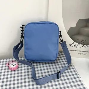 Bolso bandolera de lona azul claro de estilo japonés sobre un fondo de mantel de cuadros
