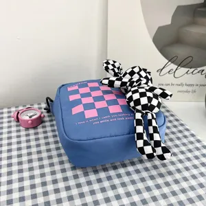 Vista detallada de un bolso bandolera a cuadros azules con un lindo muñeco de conejo a cuadros