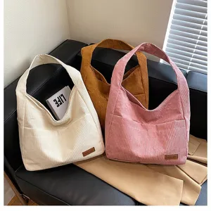 High-quality texture detail of colorful corduroy tote bags on a stylish leather sofa