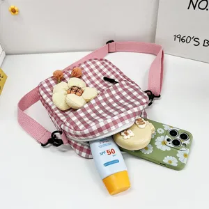 Detalle del mini bolso bandolera a cuadros rosa con flor de peluche y accesorios