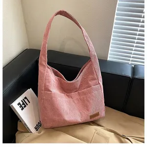 Close-up detail of pink corduroy tote bag showing striped texture and side pockets