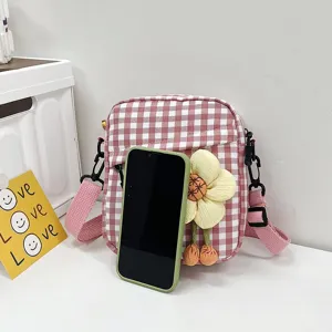 Detalle de mini bolso bandolera a cuadros rosa con un gran adorno de flor amarilla