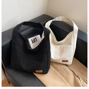 Detailed view of black and cream large capacity corduroy tote bags on a black sofa