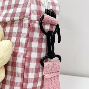 Primer plano de la correa de un bolso de cuadros rosas con un mosquetón negro