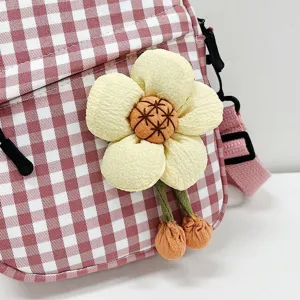 Primer plano del detalle de la flor de tela 3D en un mini bolso bandolera de cuadros.