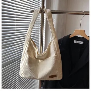 Detailed macro view of cream corduroy shoulder bag with leather patch in soft window light