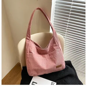 Detailed view of a pink corduroy shoulder tote bag with a small leather logo patch