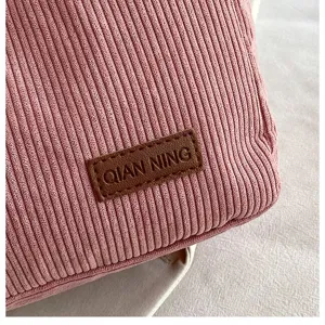 Close-up detail of pink corduroy tote bag showing ribbed texture and brand patch