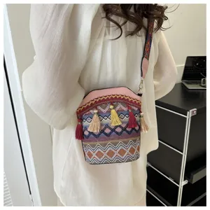 Ethnische Eimertasche mit buntem Webmuster und Quasten-Anhängern am Modell