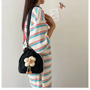 Detailansicht einer schwarzen Canvas-Beuteltasche mit einer großen weißen Blumenverzierung.