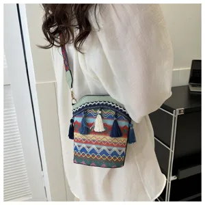 Ethno-Beuteltasche mit bunten geometrischen Mustern und Quasten, crossbody getragen.