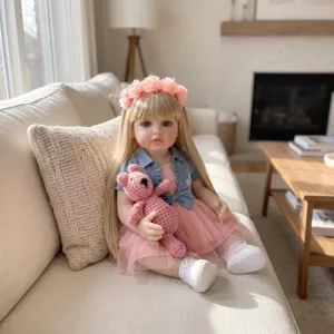 Vue détaillée de la poupée reborn Betty de 22 pouces en robe rose assise sur un canapé