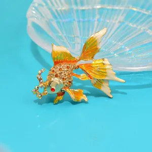Close-up of a sparkling goldfish brooch featuring detailed rhinestones and orange enamel fins