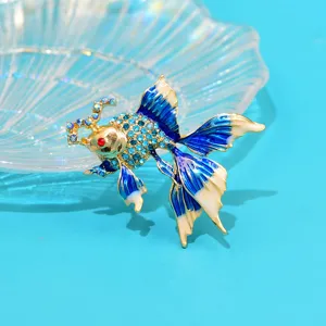Detailed macro view of an elegant goldfish brooch with blue rhinestones and enamel