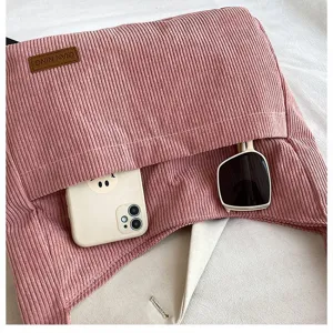Close-up of pink corduroy tote bag showing spacious pocket with phone and sunglasses