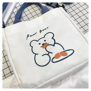 Detailansicht einer weißen Canvas-Tasche mit süßem Bären-Print und blauem Riemen.
