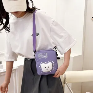 Vista detallada de un bolso bandolera de nailon violeta con cabeza de oso de peluche en modelo
