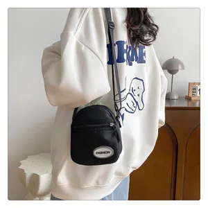 Primer plano de un bolso bandolera de nailon negro sobre una sudadera blanca