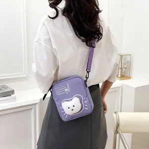 Primer plano de un bolso bandolera de nailon morado con un lindo parche de peluche