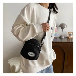 Vista detallada de un elegante bolso bandolera de nailon negro usado con ropa informal.