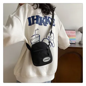Bolso bandolera pequeño de nailon negro sobre una moderna sudadera con capucha blanca oversize.