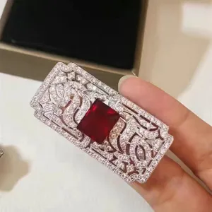 Vista macro dettagliata di un'elegante spilla rettangolare con gemma rossa e pavé di zirconi