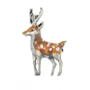 Detailed macro view of a vintage enamel sika deer brooch with white spots and silver antlers.