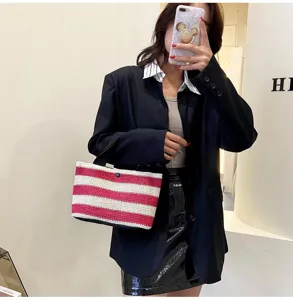 Gros plan d'un sac à main en paille tressée à rayures rouges et blanches pour femme.