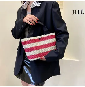Vue détaillée d'un sac à main tissé à rayures rouges et blanches porté par un mannequin