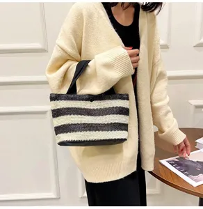 Détail d'un sac à main tissé à rayures noires et blanches porté par une femme chic