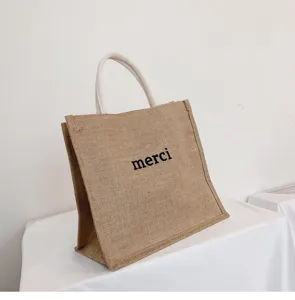 High-quality detailed view of large capacity jute tote bag with merci print design