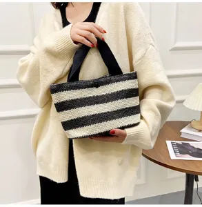 Vue détaillée d'un sac cabas tissé à rayures noires et blanches porté par un mannequin en extérieur