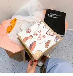 Detailansicht einer Jute-Tragetasche mit Brot-Illustrationen auf einem Lifestyle-Tisch