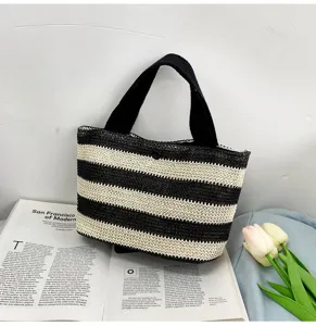 Vue détaillée d'un sac à main en paille tissée à rayures noires et blanches sur un magazine