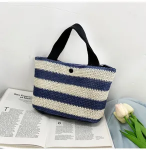 Élégant sac à main en paille tressée à rayures bleues et blanches sur un magazine