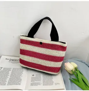 Sac à main décontracté en paille tissée à rayures avec poignées noires sur livre