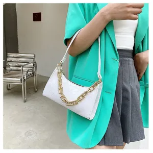 Detalle de bolso sobaquero blanco con relieve de cocodrilo y cadena dorada elegante.