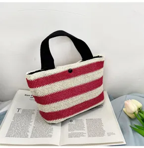 Gros plan d'un sac à main en paille rayé rouge et blanc posé sur un magazine ouvert