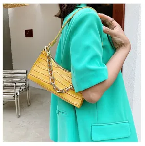 Elegante bolso baguette amarillo con efecto cocodrilo y una cadena gruesa dorada