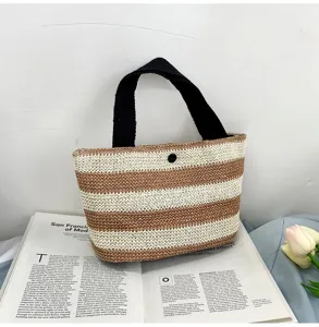 Vue détaillée d'un sac à main rayé en paille avec anses noires et texture naturelle