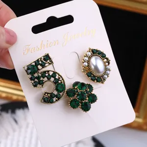 Elegant vintage three-piece brooch set featuring green crystal number 5 and pearl