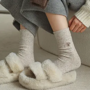 Close-up view of cozy knit wool mid-tube socks with cute dog embroidery and fluffy slippers.