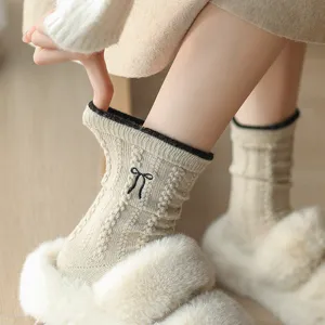 Detailed shot of women knit wool mid-tube socks with cute bow embroidery and contrast trim.