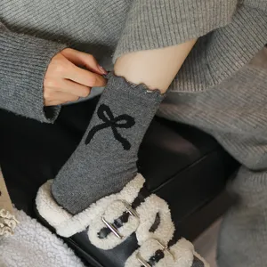 Grey knit mid-tube socks featuring black bow detail, comfortable winter sock close up.