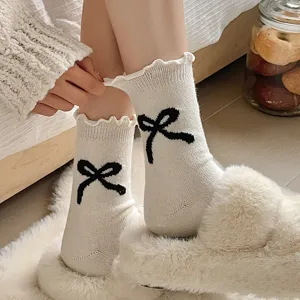White knitted mid-calf socks featuring cute black bow detail and ruffled edge for women.