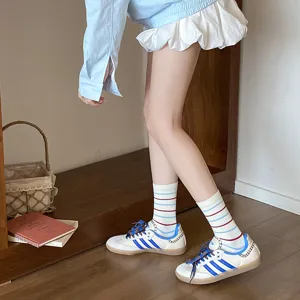 Détail des chaussettes mi-mollet en coton à rayures rouges et bleues de style preppy.