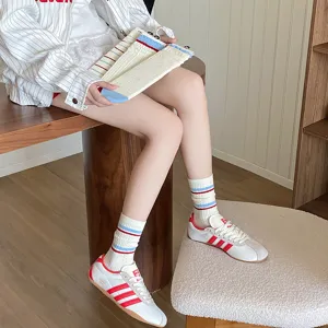 Gros plan de chaussettes en coton blanc avec rayures rouges et bleues de style collège.